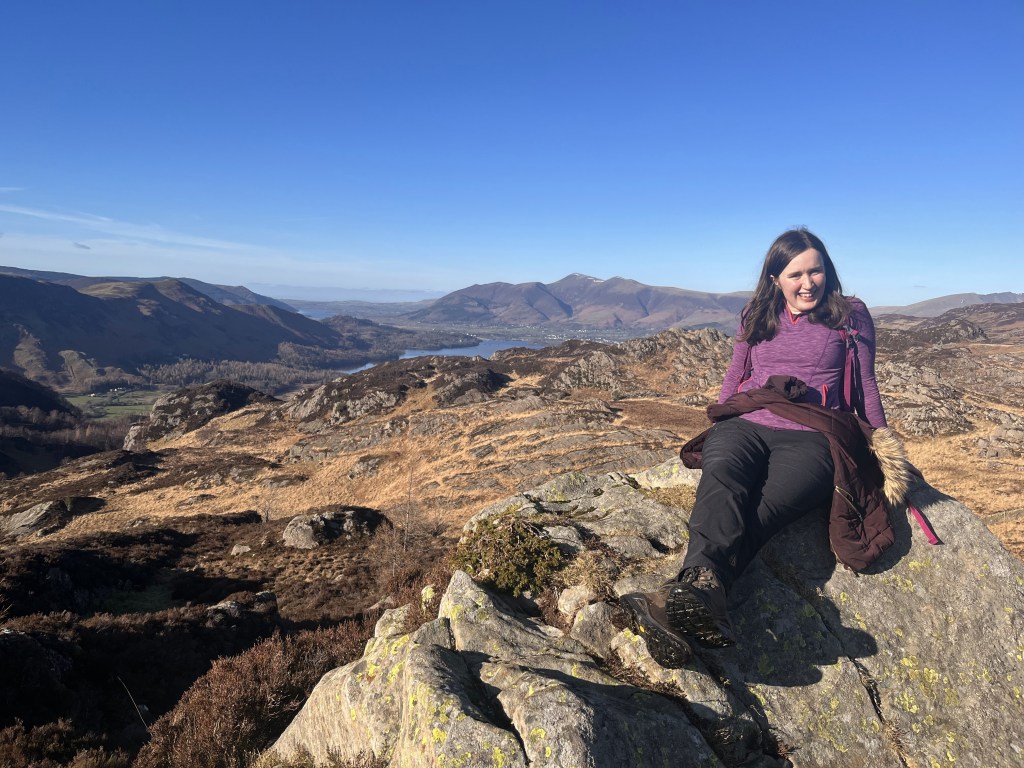 Girl smiling in the sunshine on top of a mountain